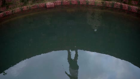 refection of sky and person walking over the well wall