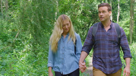 loving couple holding hands in countryside hiking along path through forest together