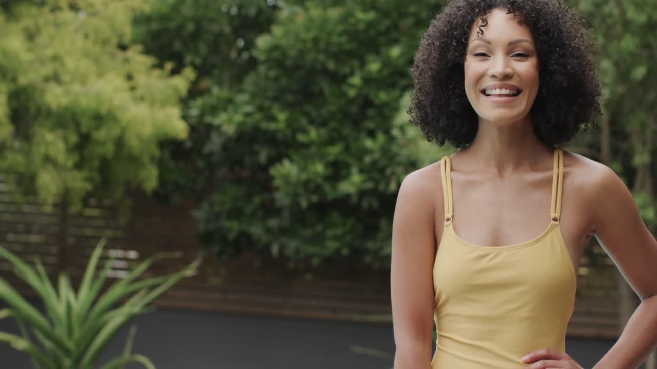 Mulher afro-americana sorrindo e olhando para a câmera no jardim, com espaço para texto, em câmera lenta, inalterado.