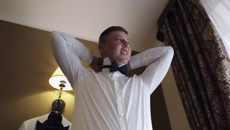 groom man adjusts bow tie, preparing to go to the bride, businessman in white shirt, wedding day