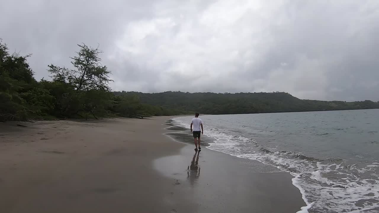hombre camina en una playa con poca gente en costa rica