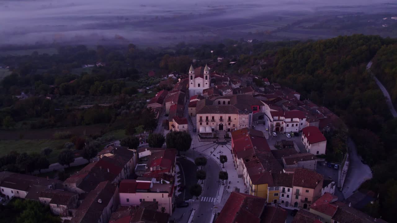 Charmerende landsby med en kirke i tåget solopgangslys.