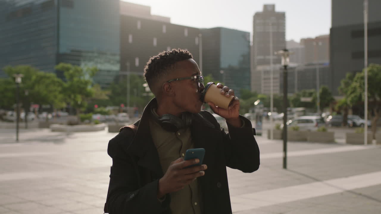 retrato de un joven afroamericano de moda estudiante bebiendo café en la ciudad relajado con gafas