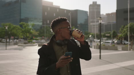 portrait of young trendy african american man student drinking coffee beverage in city relaxed wearing glasses