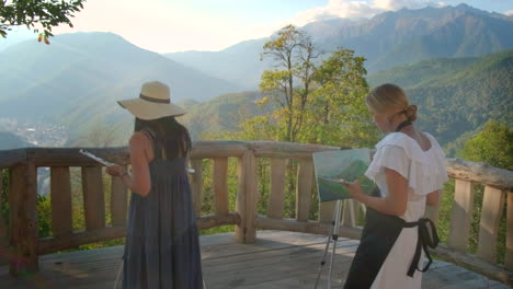 two women painting a mountain landscape