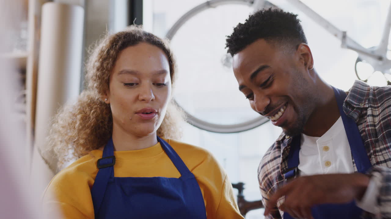 Multi-Cultural Team Of Trainees In Workshop Assembling Hand Built Bicycle Frame Together