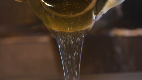 pouring strained golden honey into jar