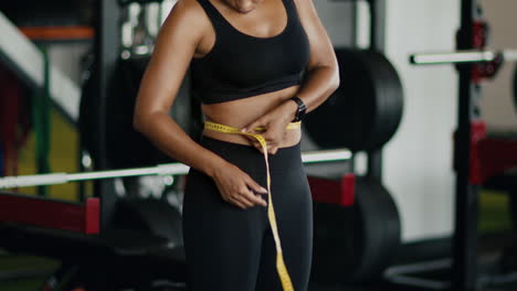woman measuring waist in gym