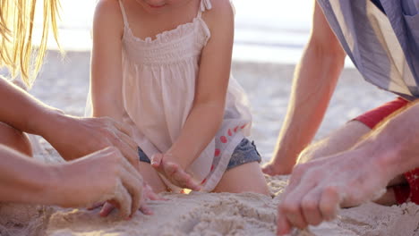 happy family playing on the beach drawing in the sand at sunset