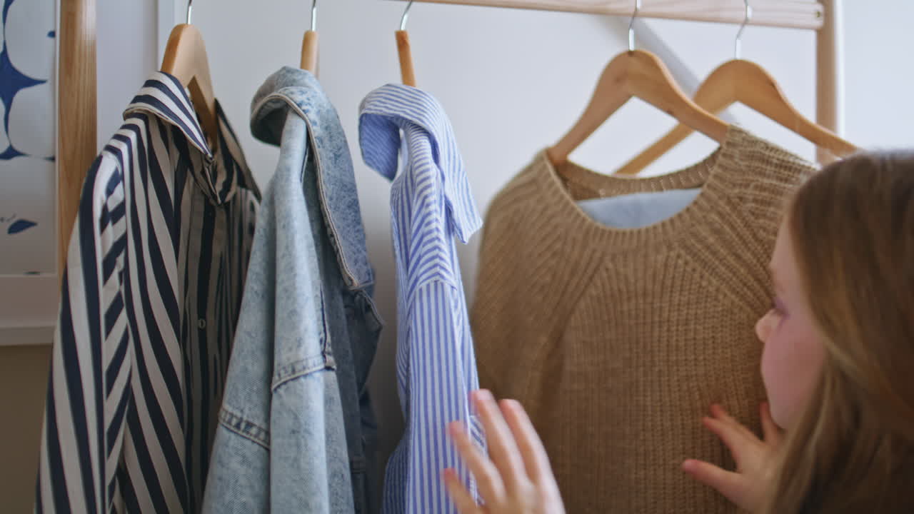 Pyjamas kid choosing dress at mothers wardrobe closeup. Back view girl playing