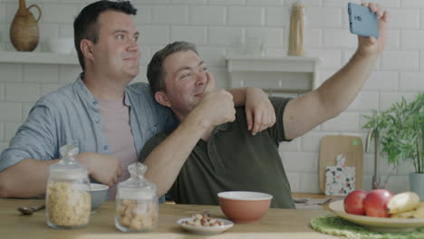 happy gay couple taking selfie during breakfast