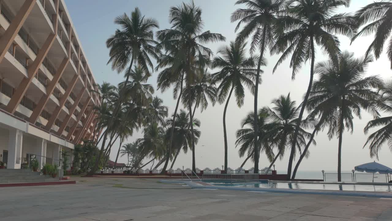 4K video of a beach side 5 star hotel with a swimming pool and palm trees