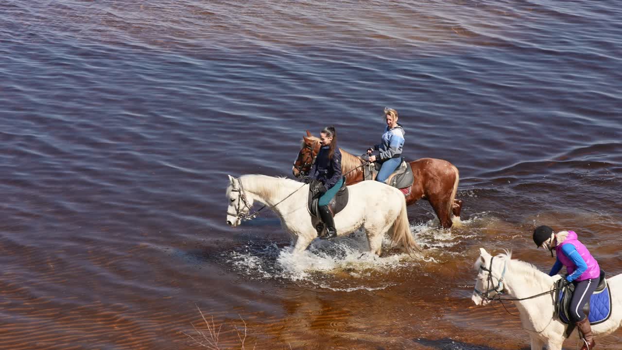 mujeres a caballo en un río