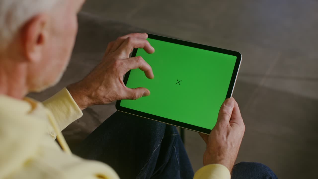 hombre mayor usando una tableta con pantalla verde