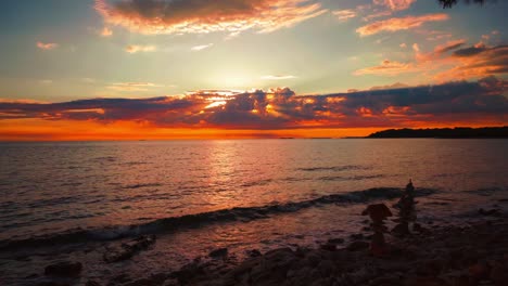 Cinemagraph---seamless-video-loop-of-of-the-sun-setting-over-the-horizon-at-a-romantic-beach-with-small-waves-at-the-Croatian-Mediterranean-seaside-with-stone-towers-and-ships-passing-by