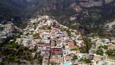 Ciudad-De-Positano-En-La-Costa-Italiana-De-Amalfi-Con-Mansiones-En-Las-Laderas-Y-Hoteles-Construidos-En-El-Acantilado,-Toma-Inclinada-Hacia-Abajo-Con-Pedestal-Aéreo