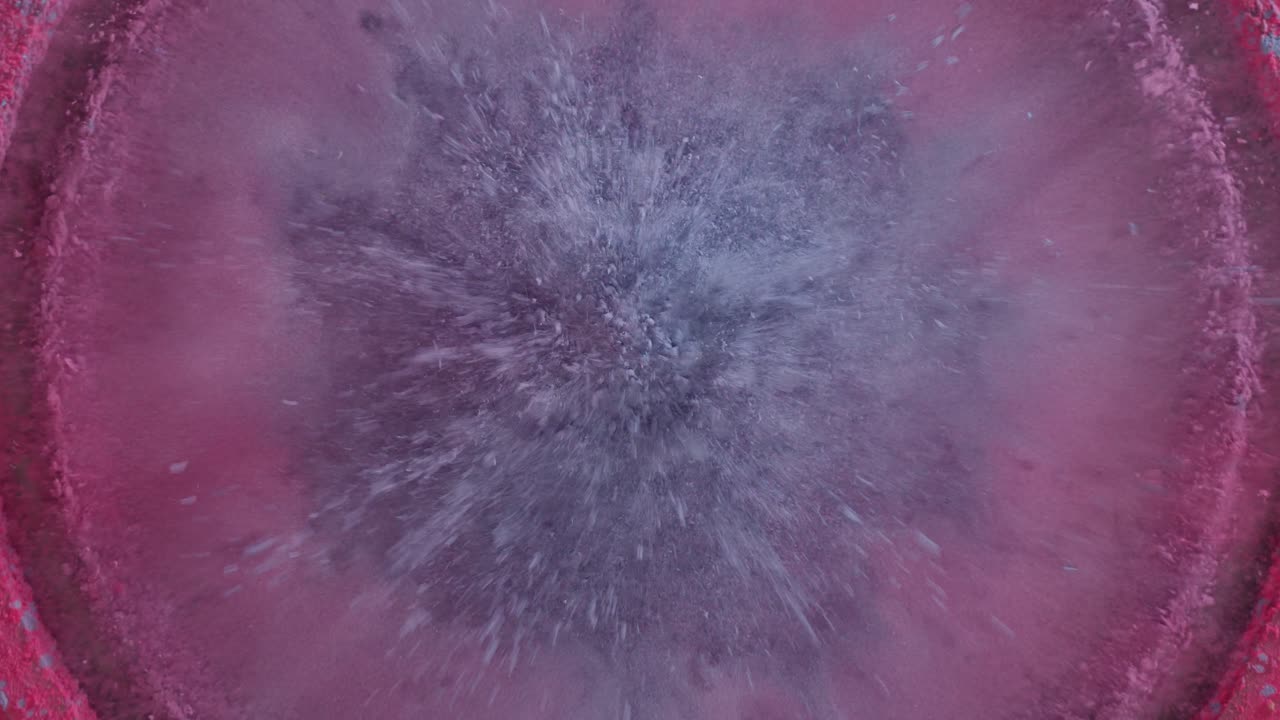 Abstrakt blåt og pink pulver vibrerer på en højttaler