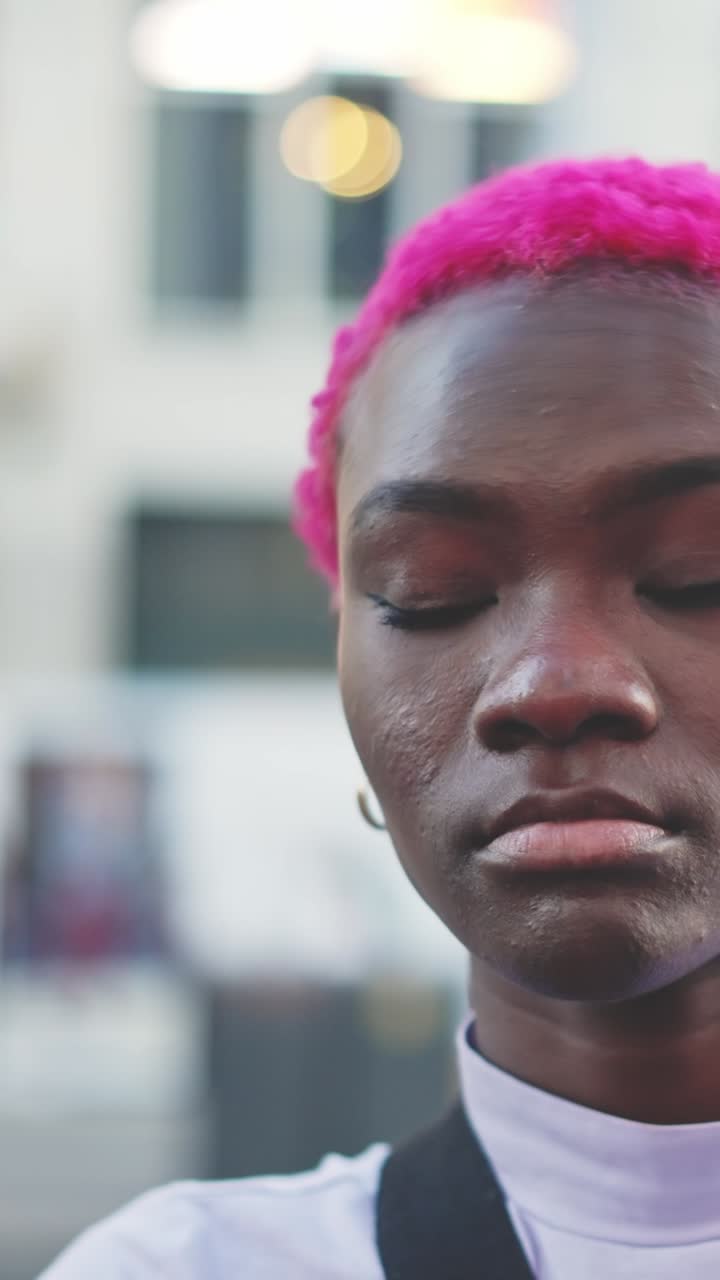 Ritratti di una persona con capelli rosa vivaci in un contesto urbano