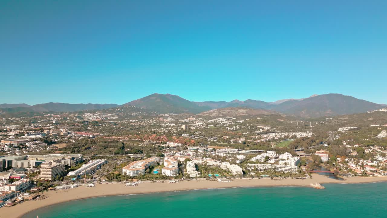 Vista aerea della spiaggia di Marbella con l'iconica montagna La Concha che si erge dietro la costa, Costa del Sol, Spagna meridionale, immersa nella calda luce mediterranea