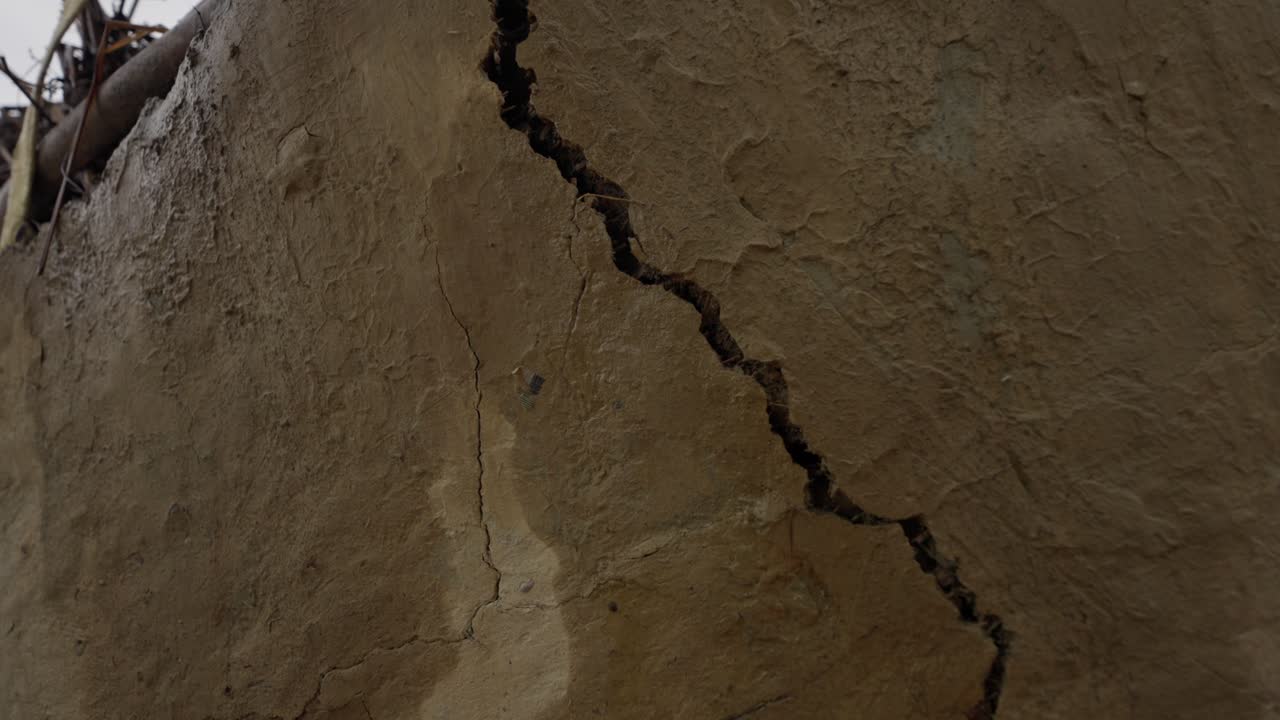 Grabación de una casa de adobe en una aldea rural mostrando una estructura parcialmente colapsada. Destaca la construcción tradicional, la arquitectura rústica y la vida rural