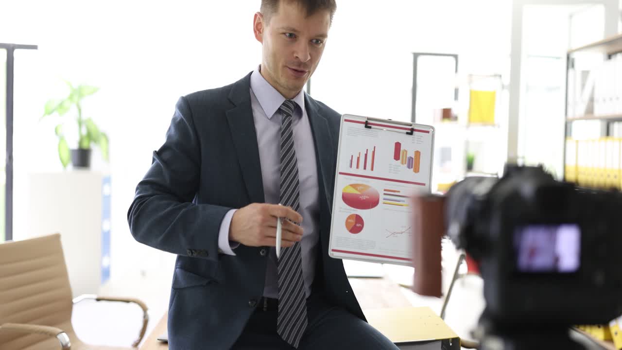 Businessman Presenting Financial Data and Charts to Camera in Office