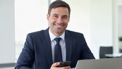 a man in a suit is smiling and holding a cell phone