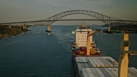 Panama-City-Aerial-V53-Cinematic-Low-Level-Drohne,-Die-An-Einem-Massengutfrachter-Vorbeifliegt,-Um-Den-Hafen-Von-Puerto-Balboa-Herum,-Fliegt-Unter-Der-Brücke-Von-Amerika-Hindurch-Mit-Blick-Auf-Den-Sonnenuntergang-–-Aufgenommen-Mit-Mavic-3-Cine-–-März-2022