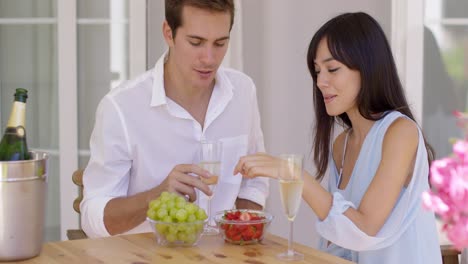 couple sipping wine and eating fruit