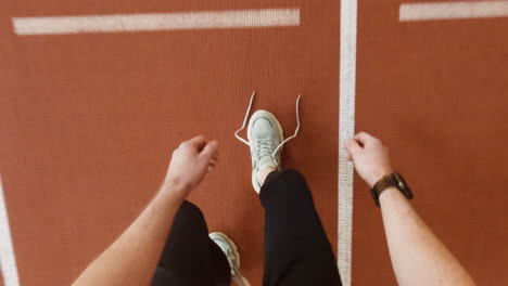 person tying shoelaces on an athletic track