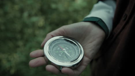 woman hand finds orientation with a compass in the mountains