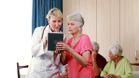 Female-doctor-assisting-senior-woman-on-digital-tablet