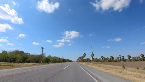 pov driving past the santa anna wildlife refuge and a palm date grove on military highway in texas near the international boarder