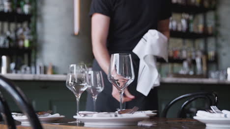 close up of male waiter polishing cutlery on table before service in bar restaurant