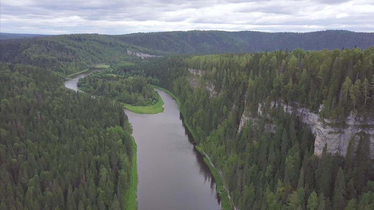 Ilmakuva mutkittelevasta joesta rehevän metsäisen laakson läpi