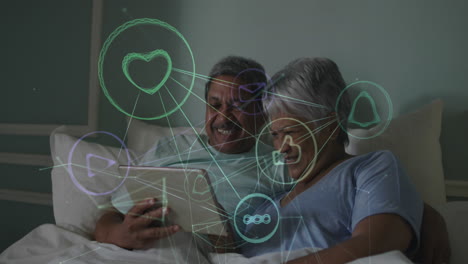 animation of network of connections with icons over senior couple using tablet in bed at home