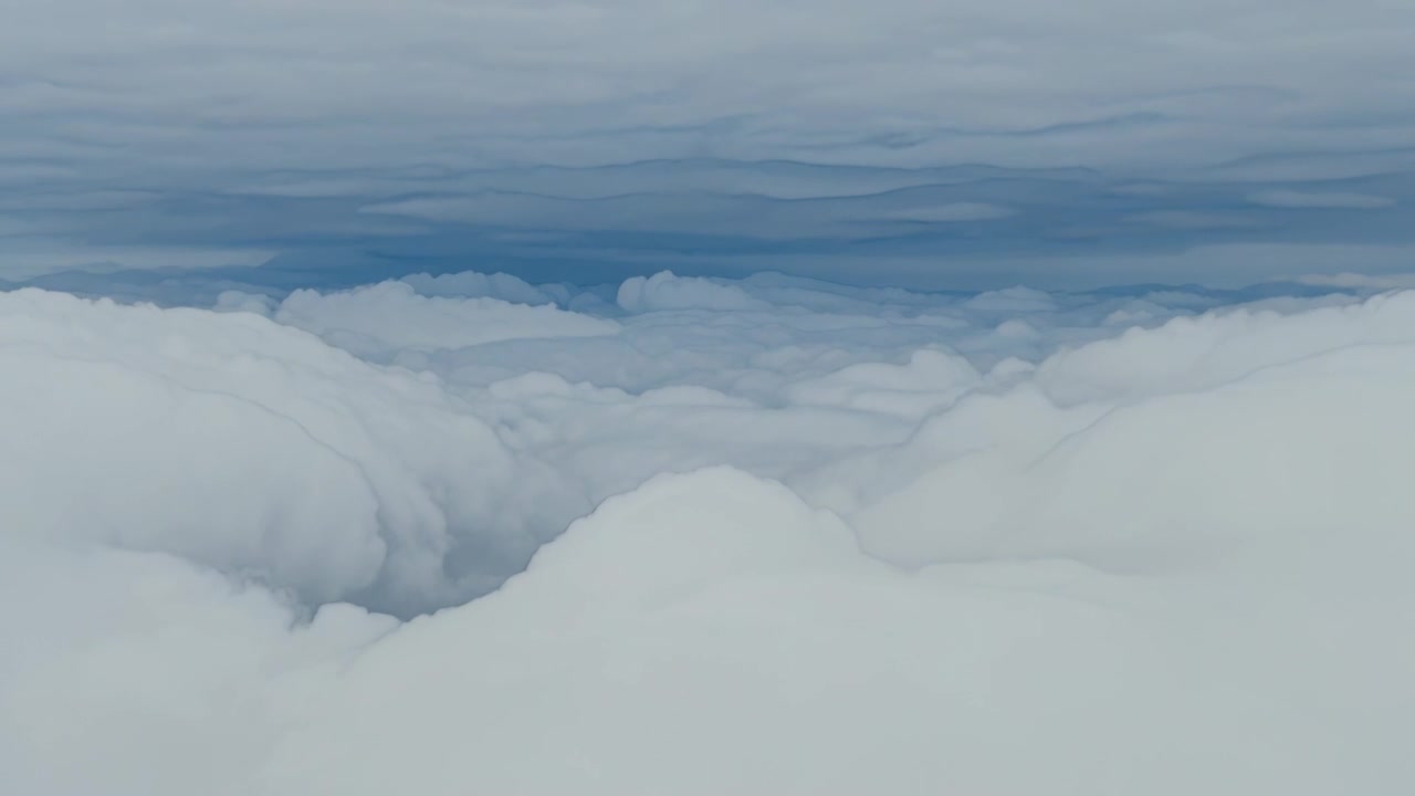 Gliding drone revealing central thick cumulus banks and ridges over open sky, sun warming layers