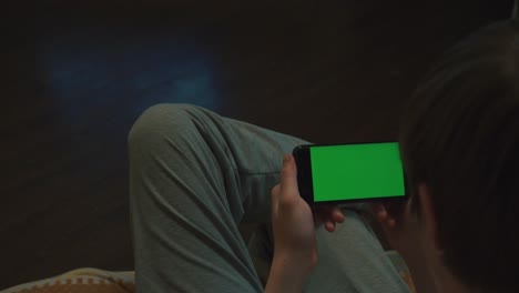 person using smartphone with green screen