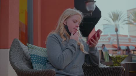 Girl-sitting-outdoors-playing-on-here-cell-phone