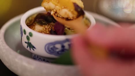 close-up of a wooden spoon garnishing a steamed egg in a decorative porcelain bowl.