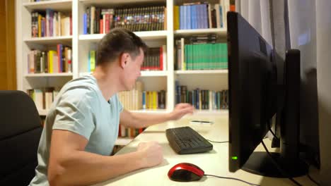 man talking on phone and reacting at computer desk