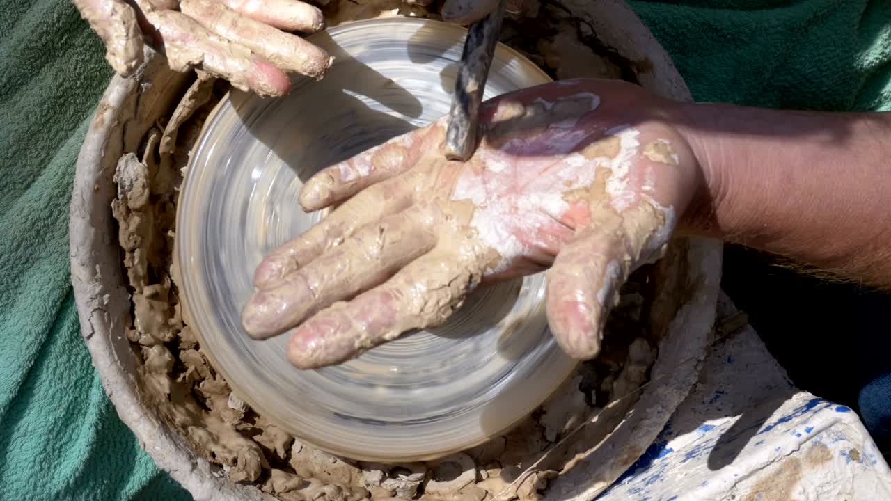 부분에서 볼 때, 도자기의 손은 도자기의 바에서 점토로 작업합니다.