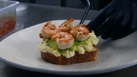 the chef puts fried shrimp on toasted bread with scrambled eggs