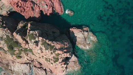 vista de arriba hacia abajo del acantilado de la montaña y el agua azul del mar tropical durante un día soleado de verano en cerdeña, italia - tiro estático aéreo