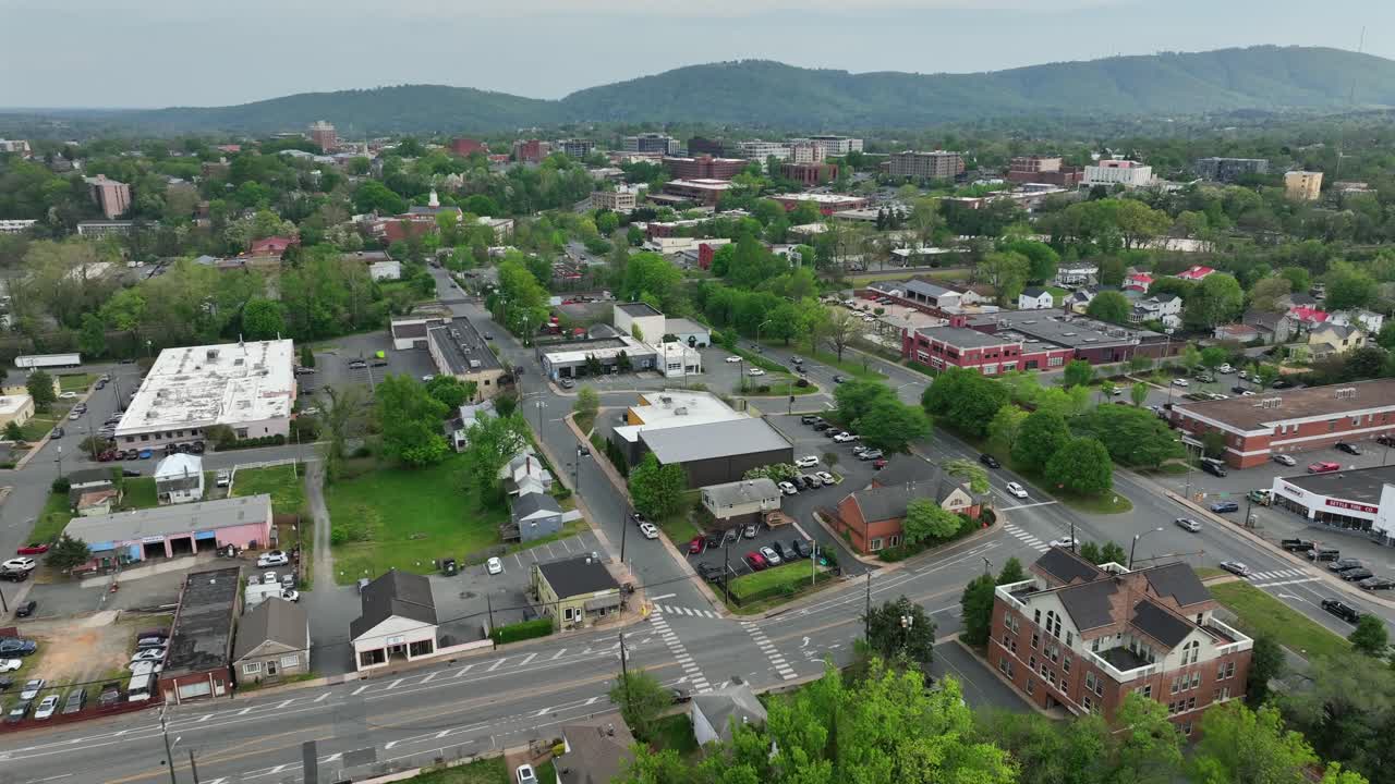 Cars on street on junction of american town at cloudy day. Aerial view. Charlottesville, Virginia. Aerial wide shot. Cloudy day in spring. City center with mountains in distance.