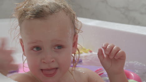 a closeup of a baby girls face who is bathing with brother