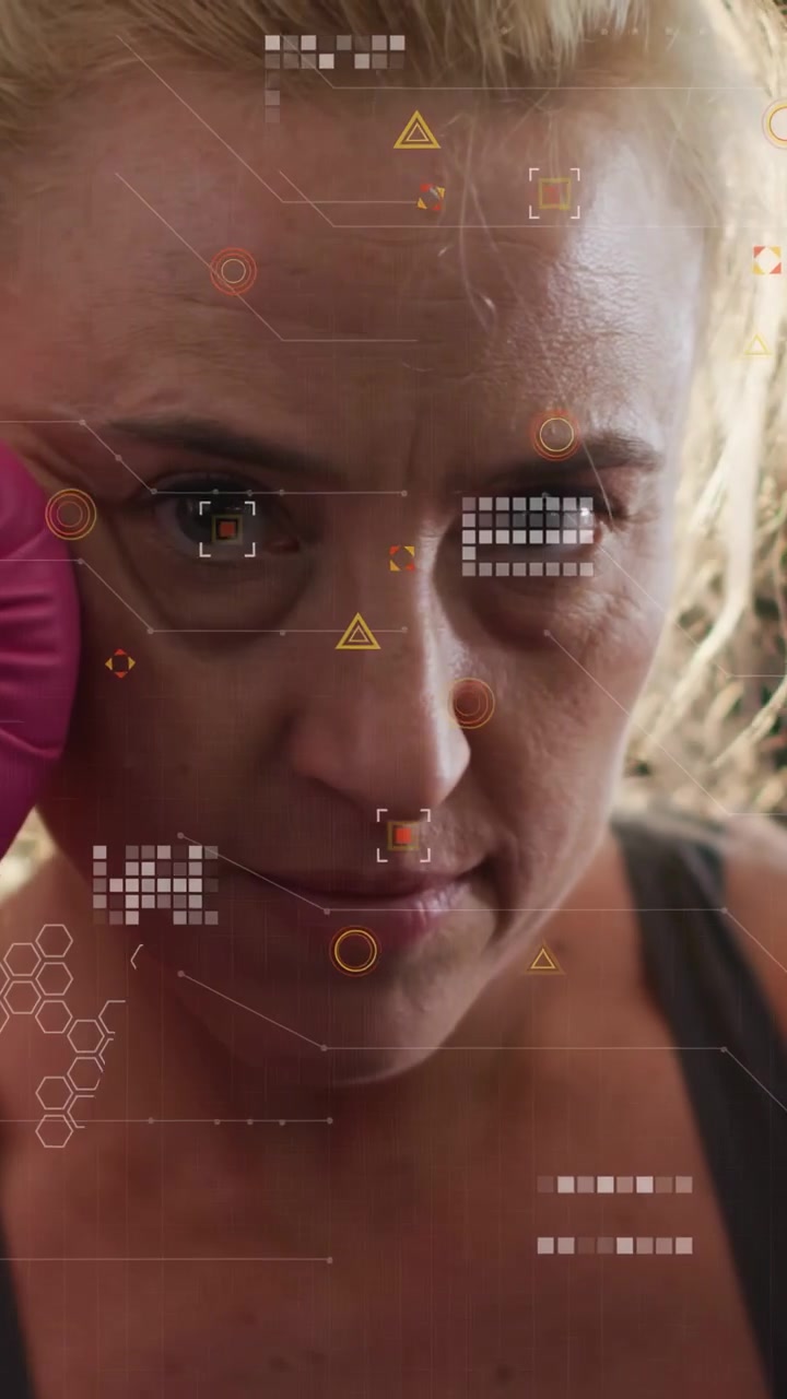 Video verticale: Donna pugile che inizia un allenamento sferrando pugni con un guantone rosa verso la telecamera, con HUD fitness che reagisce.