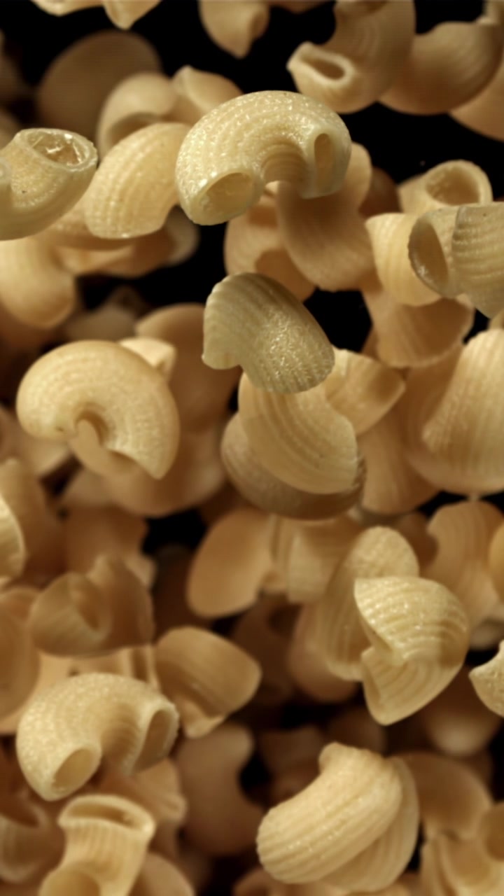 Pasta di maccheroni a gomito secchi che cadono al rallentatore