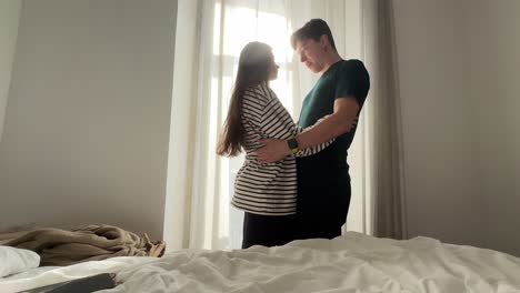 Couple Hugging by Window in Bedroom