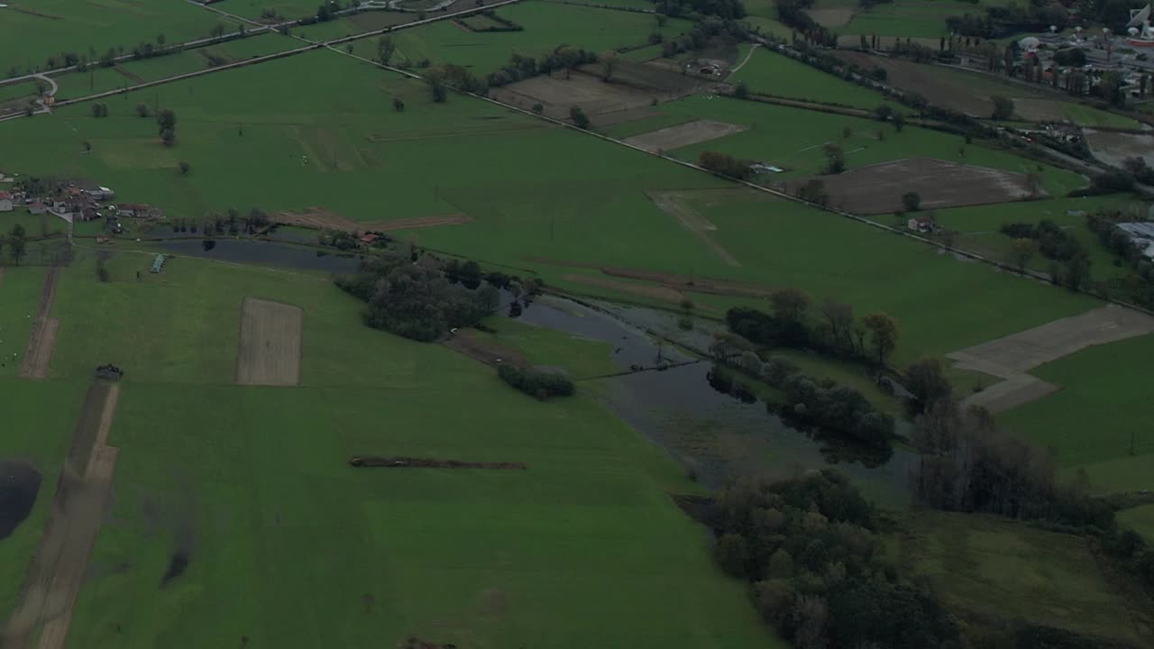 Aerial view of green fields and rivers in the Italian Alps