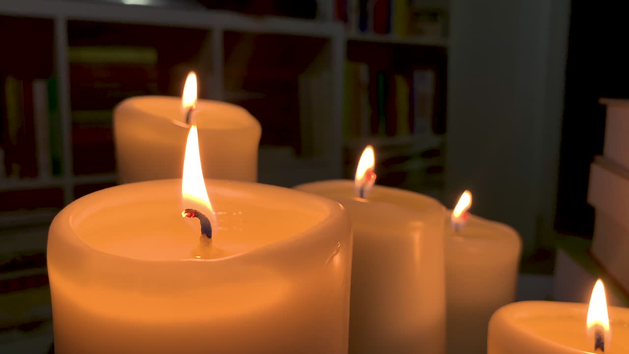 Alcune candele accese l'una accanto all'altra, la fiamma oscilla al rallentatore.